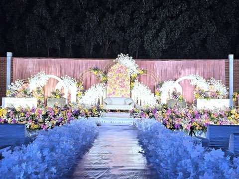 Pink reception stage with a blue floral aisle on the lawn at night