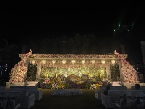 Marigold-draped stage with mirror backdrop lit up at night on the lawn