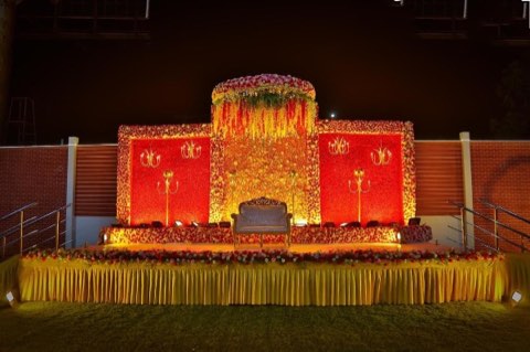 Outdoor reception stage in red and gold on the lawn at Jaithri Grand Convention
