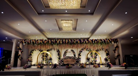 Peach and gold floral stage with golden rings under three chandeliers in the main hall